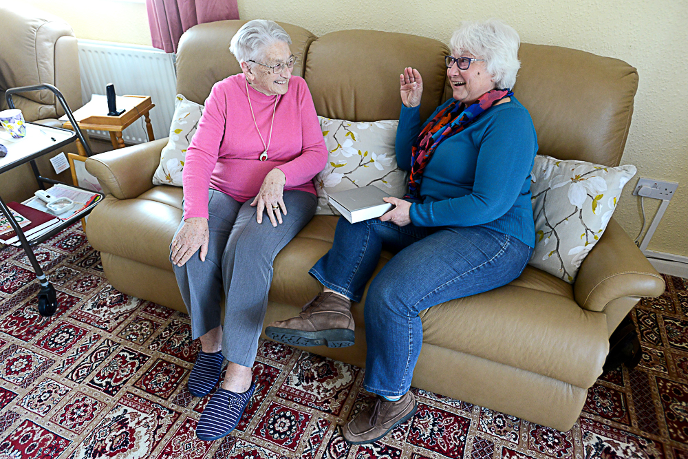 A client and a befriender from LLBS sat on a sofa together talking to each other.