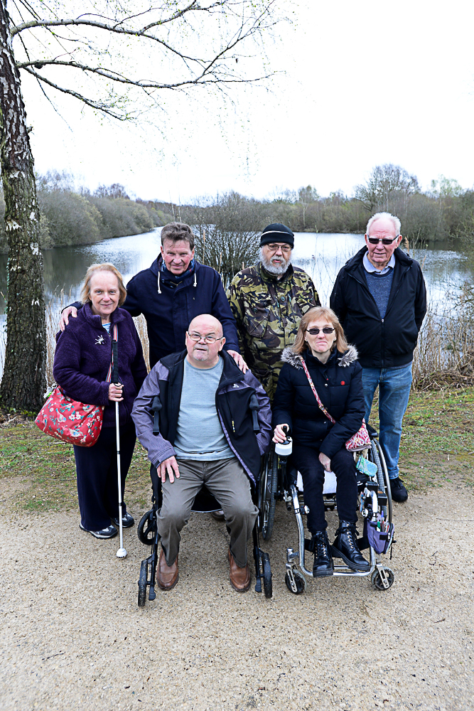 The Whisby Walking group positioned infront of the water on a bright day.